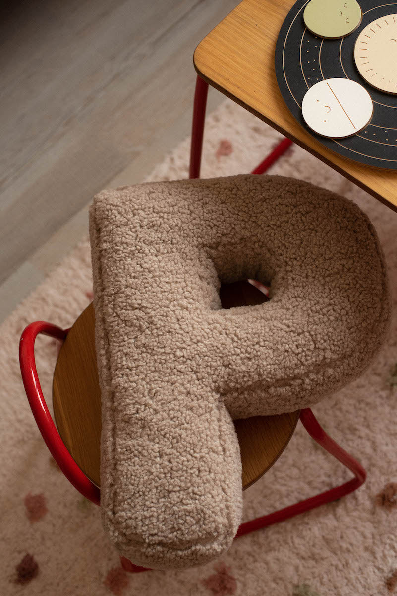 boucle letter cushion p mocha lying on kids chair. teddy cushion