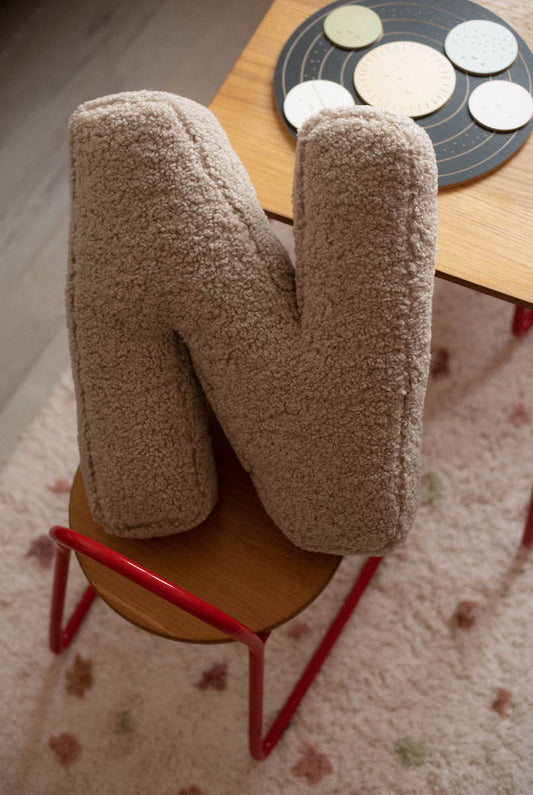 boucle letter cushion N mocha on kids chair. teddy pillow