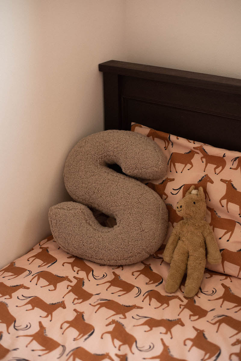 boucle letter cushion S mocha by bettys home lying on kids bed. teddy pillow