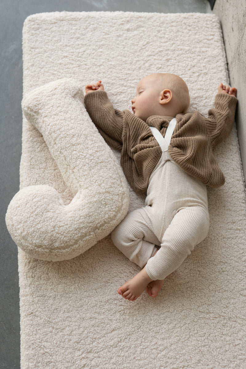 little baby on boucle mattress sleeping next to boucle letter cushion by bettys home