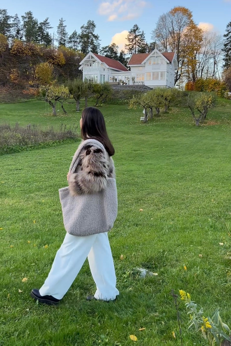 woman walking in garden with boucle shopper bag by bettys home. boucle tote bag 