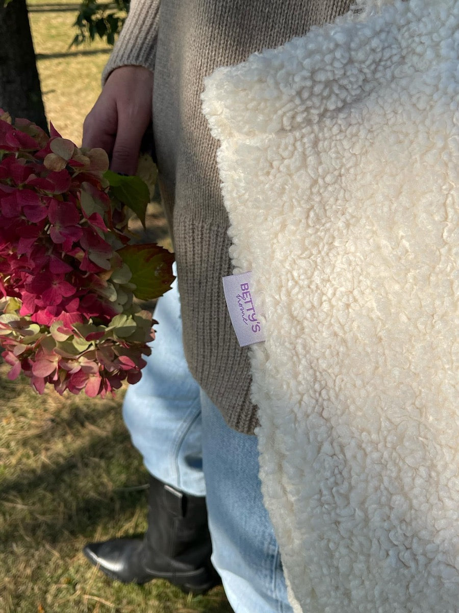 woman in garden next to trees with boucle shopper bag. Fashionable bouclé tote bag for everyday use. boucle tote bag b