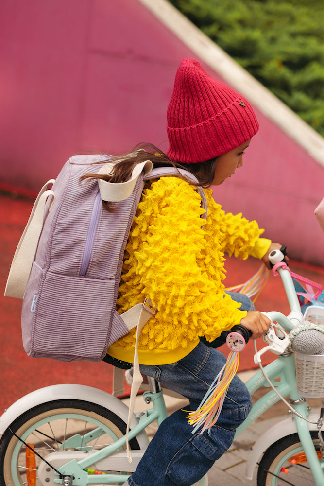 little girl on bicykle with corduroy backpack in lilac by bettys home