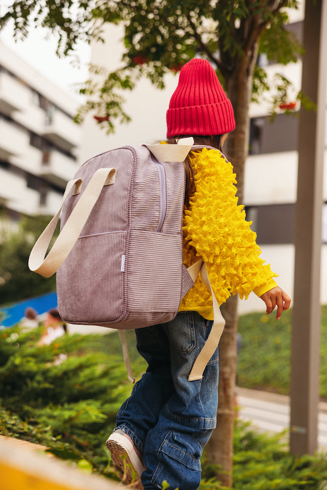 little girl in yellow jacket on playground with corduroy backpack in lilac by bettys home