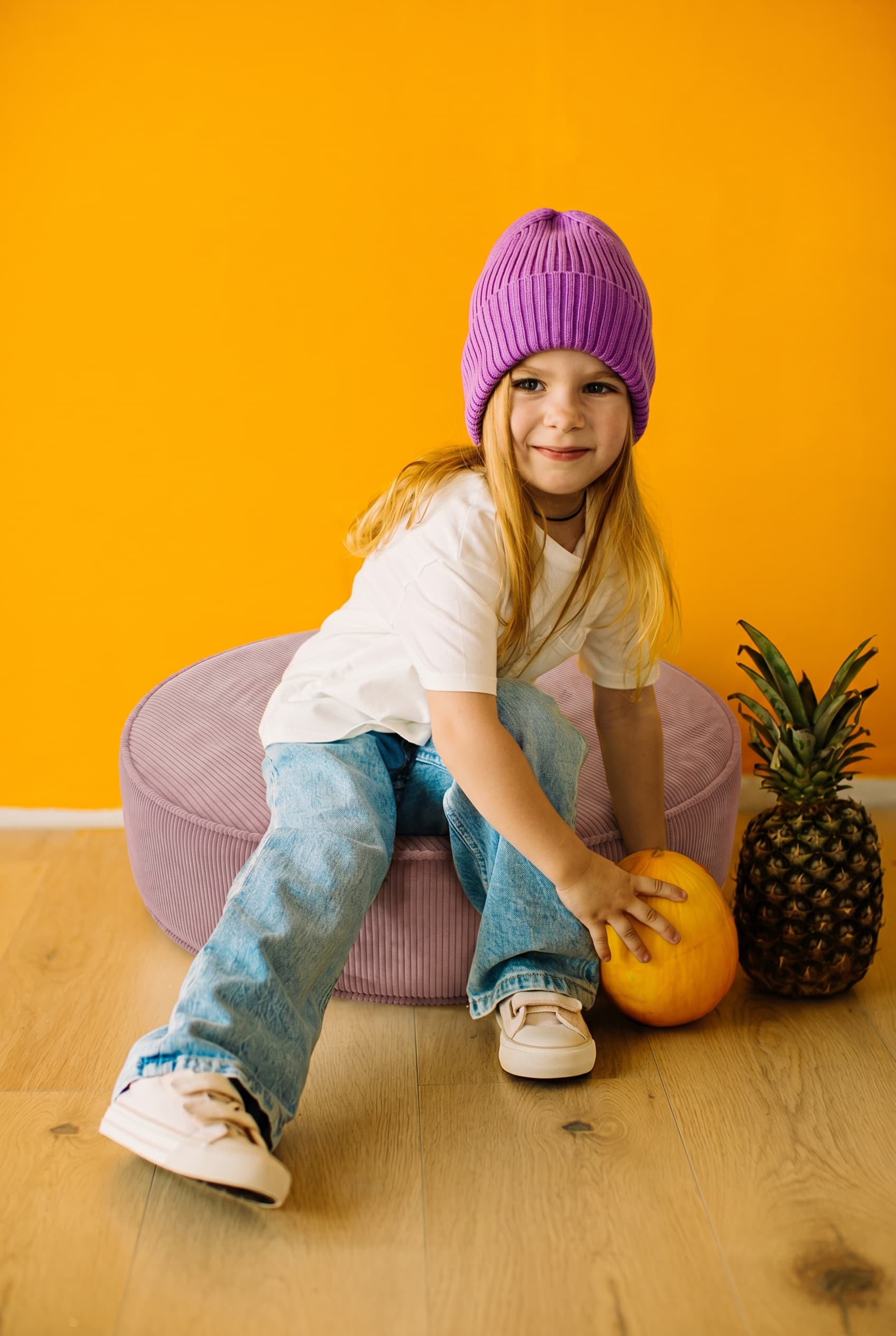Little girl sitting on large corduroy floor pouf lavender by Bettys home 