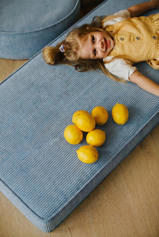 child on corduroy mattress blue by Bettys home. on mattress there are also lemons 