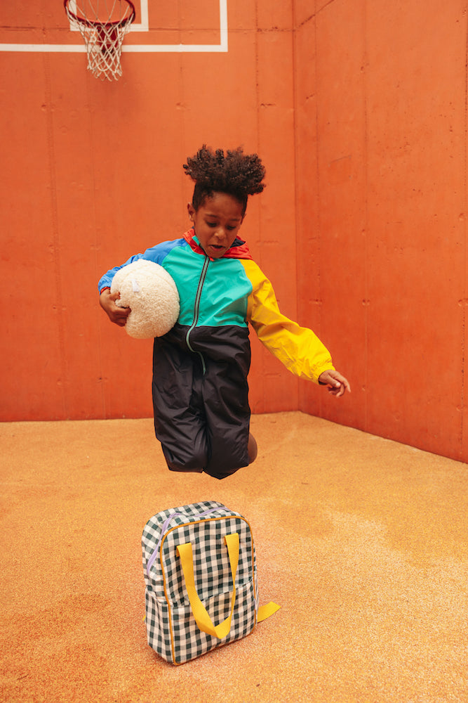 boy skipping gingham backpack with boucle ball in hands. Green gingham backpack by bettys home