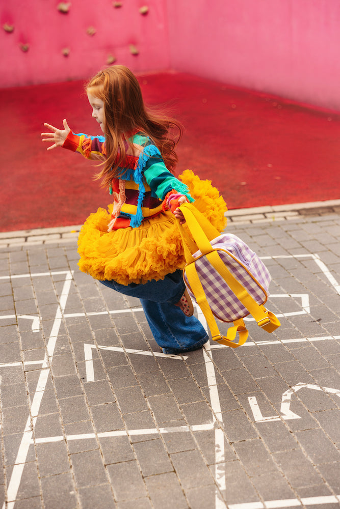 girl playing outside with a gingham backpack by bettys home