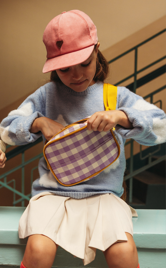 girl sitting on wall with yellow gingham fanny pack by bettys home. gingham hip pack