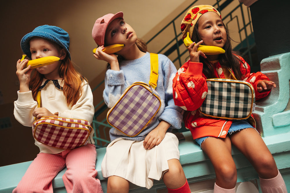 girls talking through banana sitting at school with gingham belt bags. gingham hip pack by bettys home