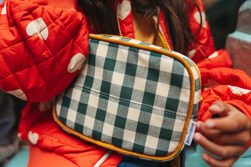 Little girl in red jacket with a green gingham hip pack by bettys home. gingham hip pack