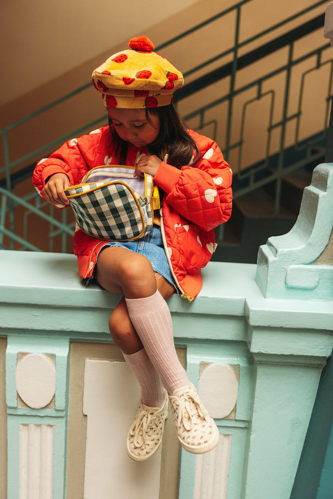 Little girl sitting on the railing with green gingham hip pack by bettys home. fanny pack gingham