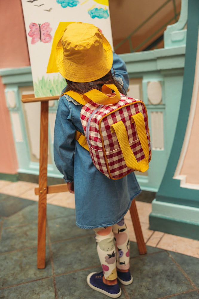 little girl looking at a picture at school with a small gingham backpack by bettys home