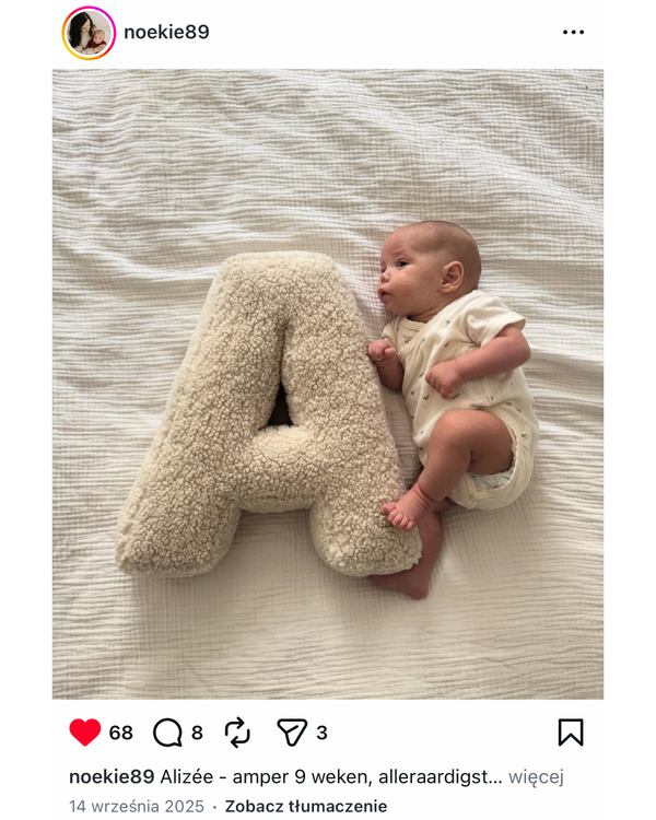 newborn on bed near to letter cushion boucle by bettys home