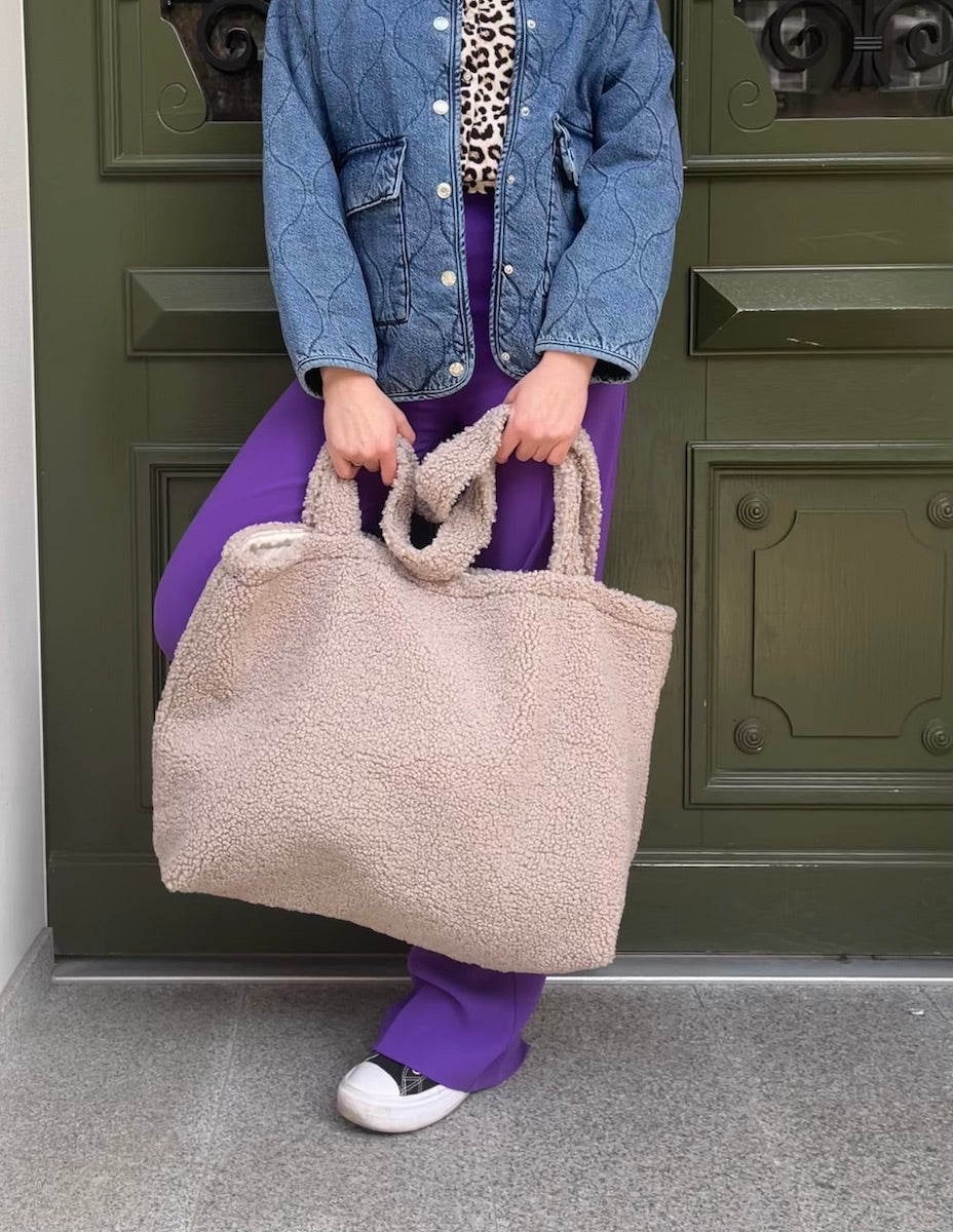 girl standing next to green door with boucle shopper bag in hands. boucle tote bag by bettys home