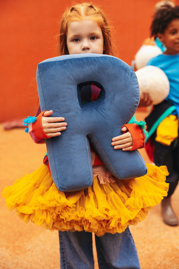 girl in yellow dress holding velvet letter cushion R blue by bettys home. letter shaped pillows