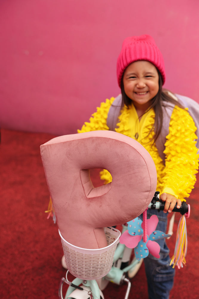 girl on bike with velvet letter cushion P in pink by bettys home. letter shaped pillows