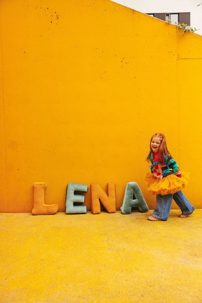 girl named LENA on yellow background with velvet letter cushions by bettys home.