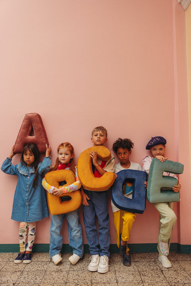 kids at school holding velvet letter cushions by bettys home. Letter shaped pillow