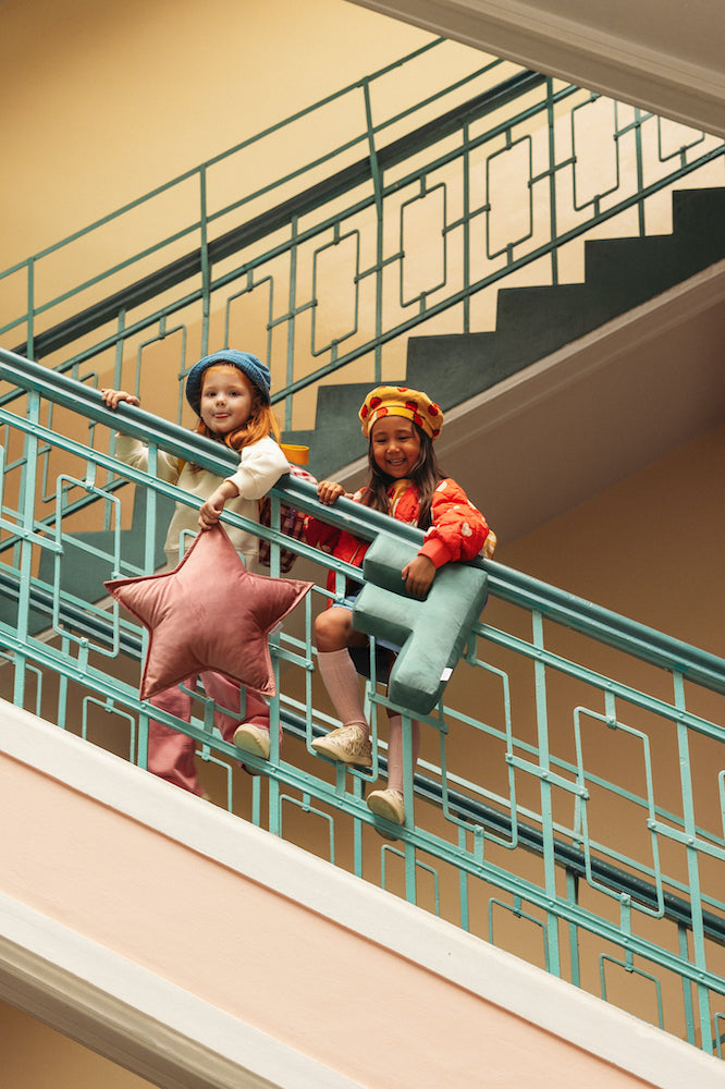 two girls standing on stairs at school with velvet letter pillow and velvet star pillow by bettys home.