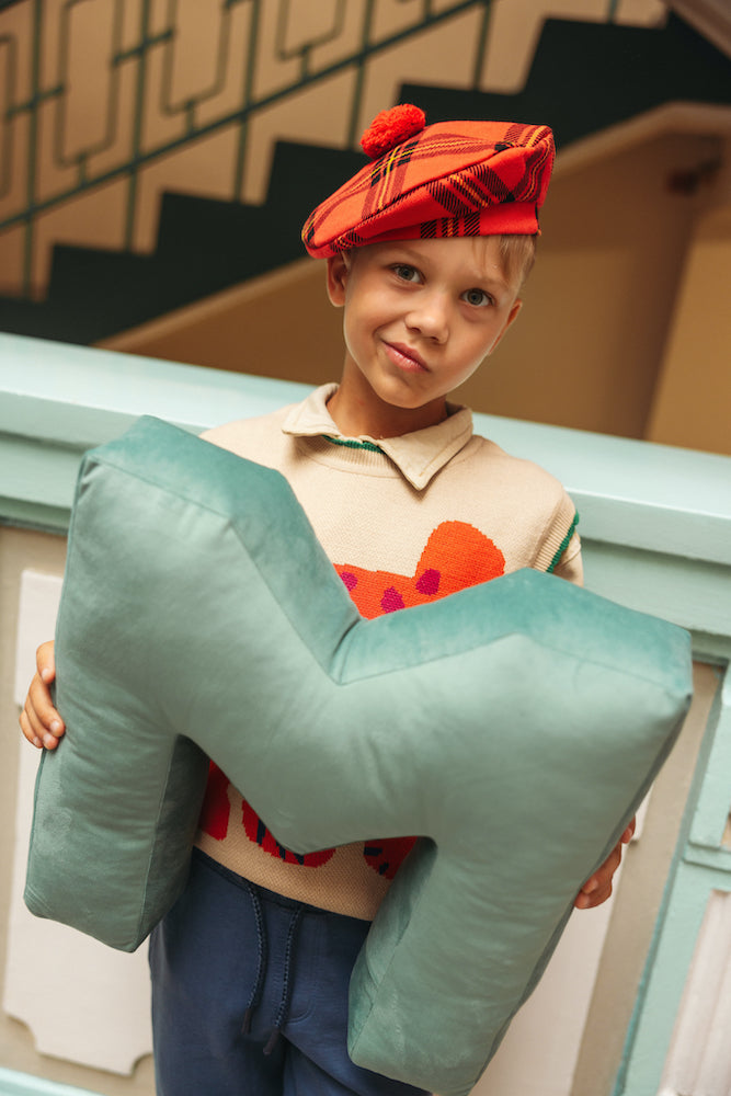 boy at school holding velvet letter m in mint by bettys home. letter shaped pillows 3